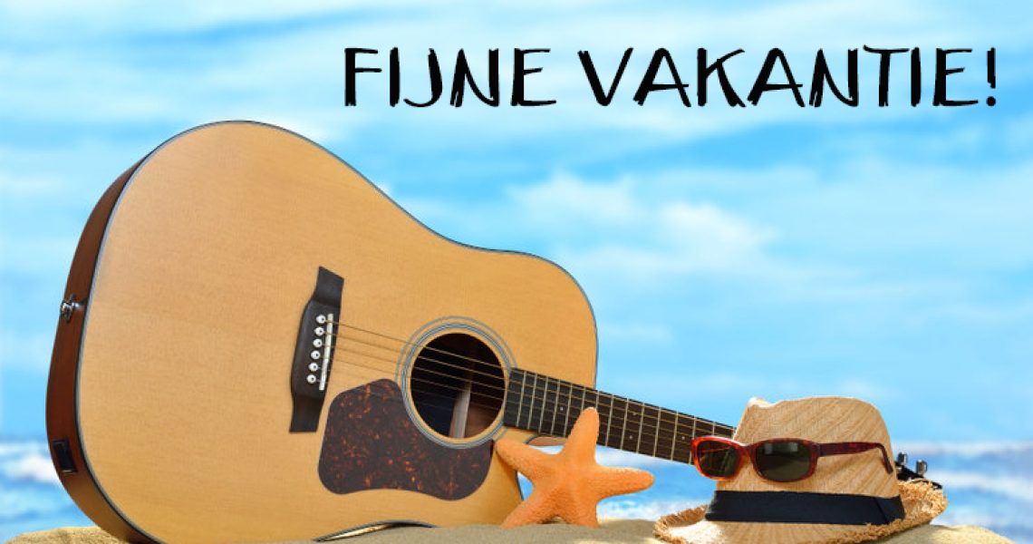Acoustic guitar on the sandy beach in summer with blue sea and sky